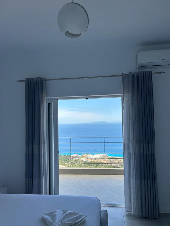 a bedroom with a window with a view of the ocean at Vila Jona Palasë in Dhërmi