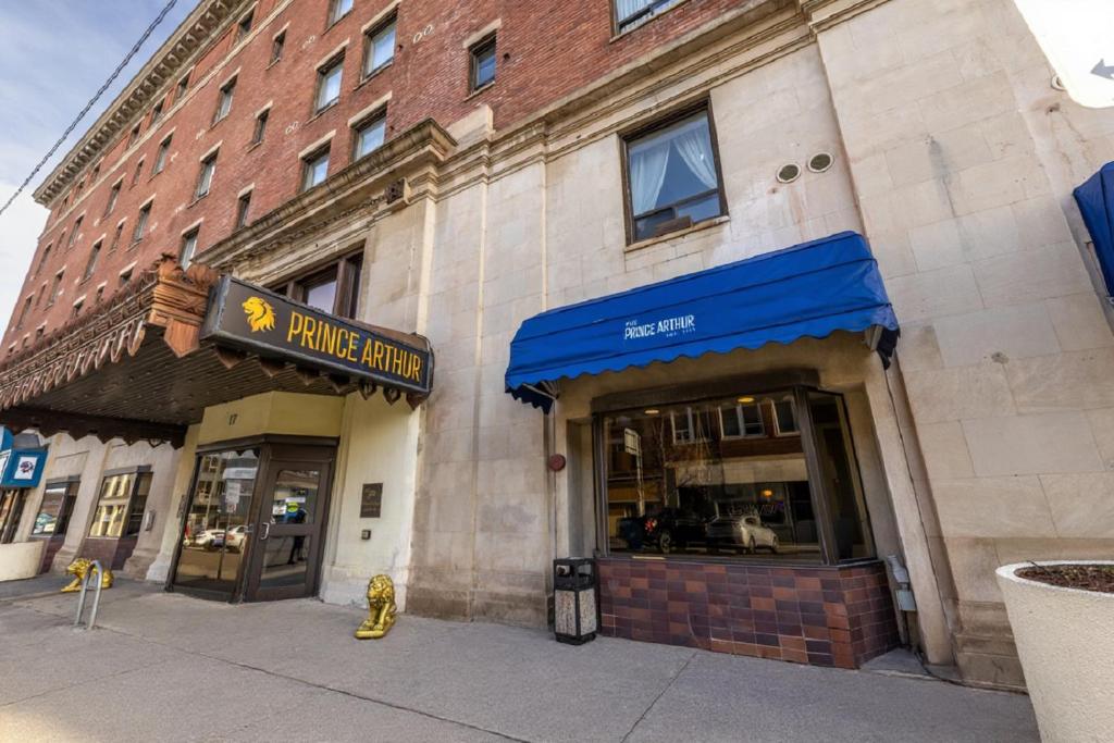 a store front of a brick building with a blue awning at The Prince Arthur Hotel in Thunder Bay