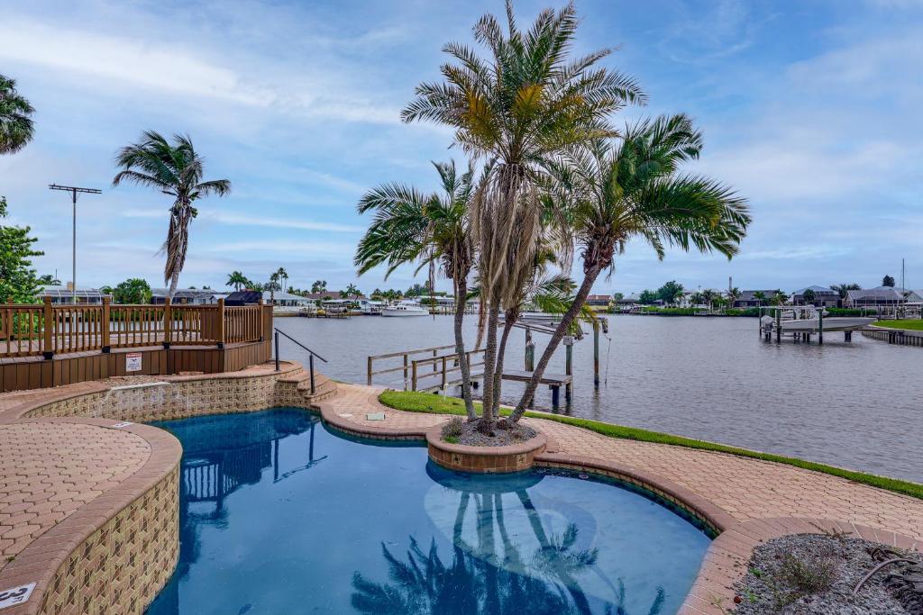 a swimming pool with palm trees next to a body of water at Pet Friendly! Canal-Front Apollo Beach Gem w/ Pool in Apollo Beach