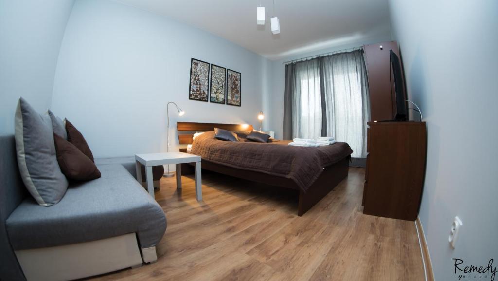 a bedroom with a bed and a couch and a table at Apartamenty Sedinum - Modern in Szczecin