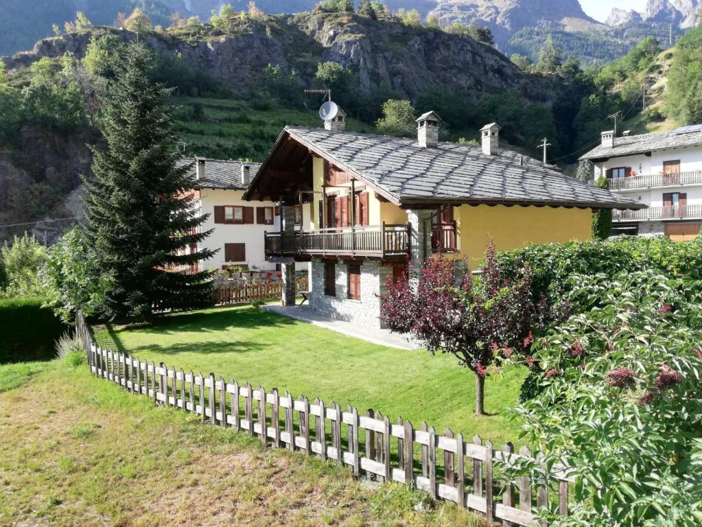 a house with a fence in front of a mountain at La Betulla in Oyace
