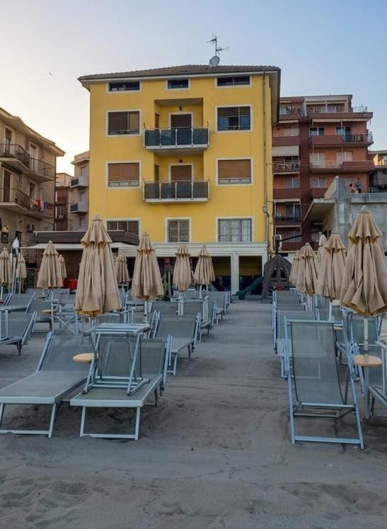 a group of chairs and umbrellas in front of a building at La Risacca in Pietra Ligure
