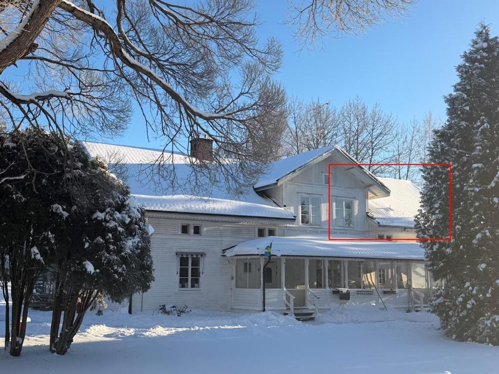 a white house with snow on the roof at Apartment Målargården in Uddeholm