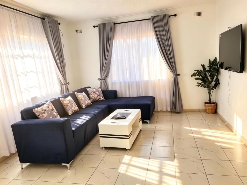 a living room with a blue couch and a tv at 2 Bed Cottage close to Westgate Shopping Centre in Harare
