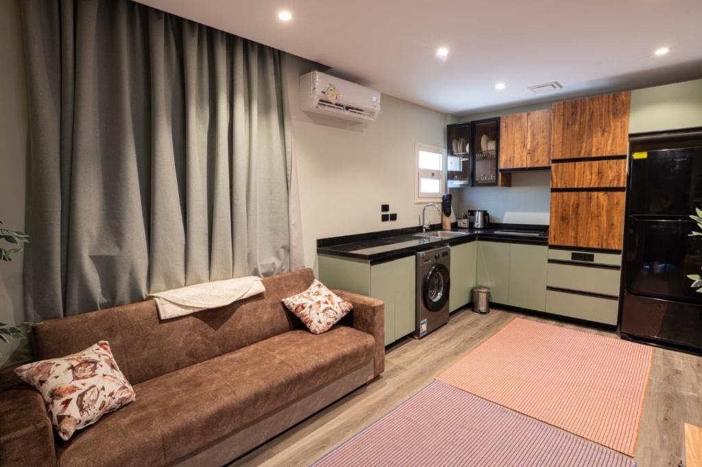 a living room with a couch and a kitchen at Cozy Studio Apartment in Sheikh Zayed in Sheikh Zayed