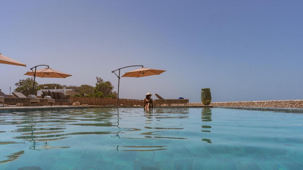 a person standing next to a swimming pool with an umbrella at Anima Ocean Lodges in Essaouira