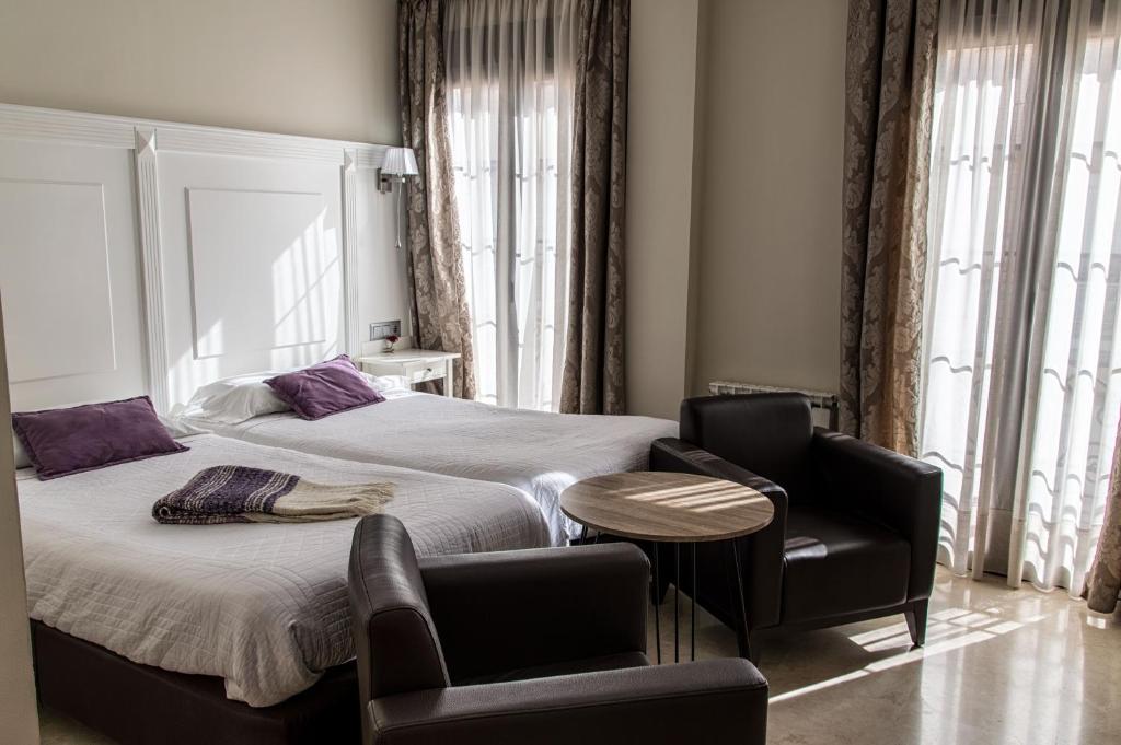 a bedroom with a bed and two chairs and a table at Hotel Sevilla in Ronda