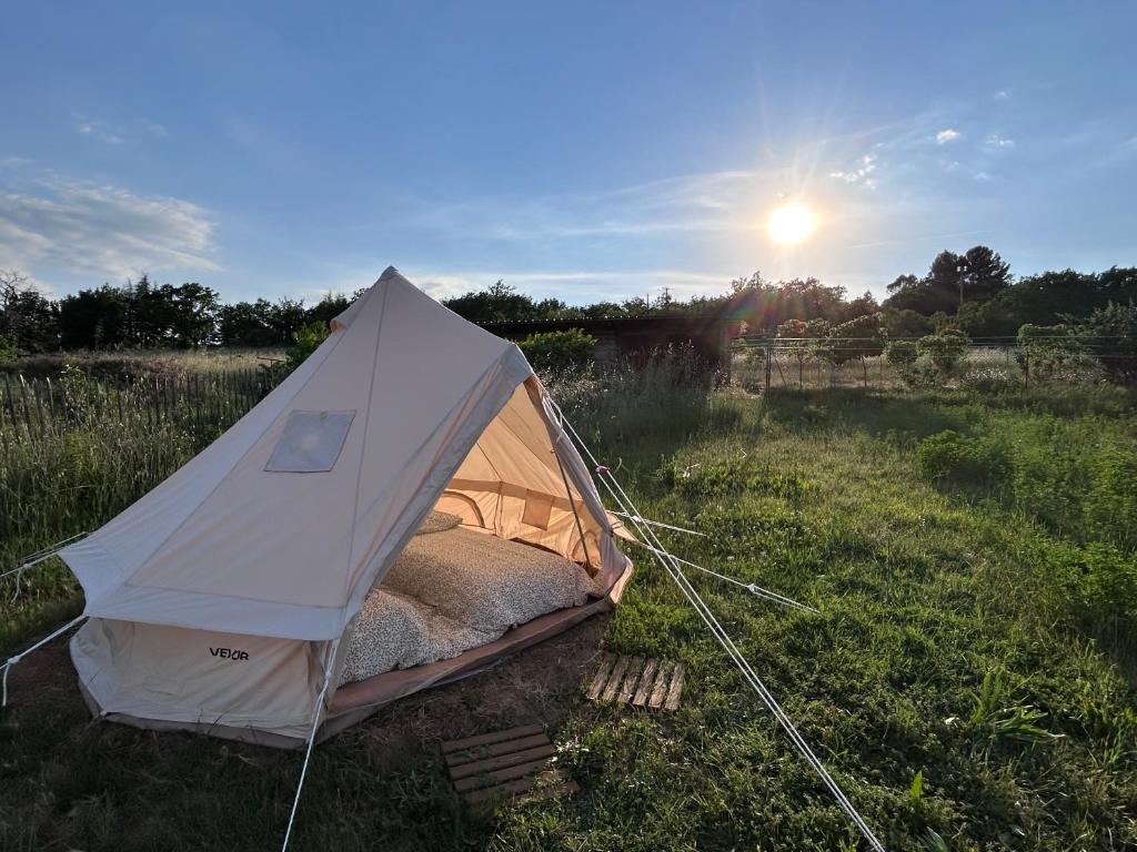 a white tent in a field with the sun in the background at Tente Cocoon in La Brillanne