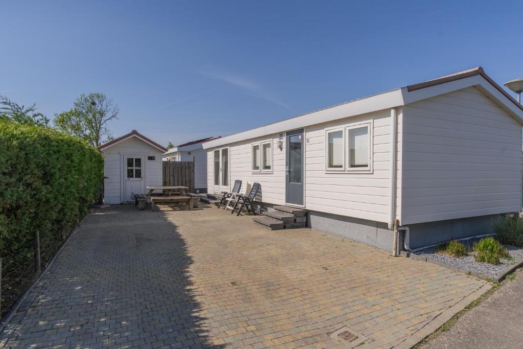 a white tiny house with a patio and a fence at Chaletparc Krabbenkreek Zeeland - Chalet 96 in Sint Annaland