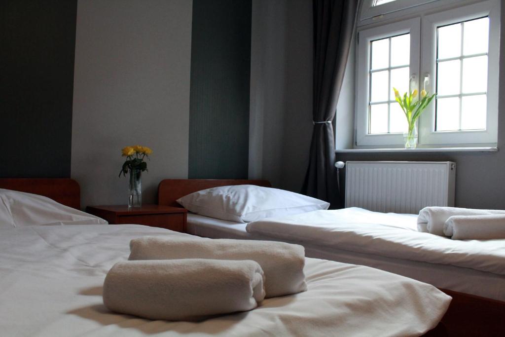 three beds in a room with a window at Dworek Mitro in Gdynia