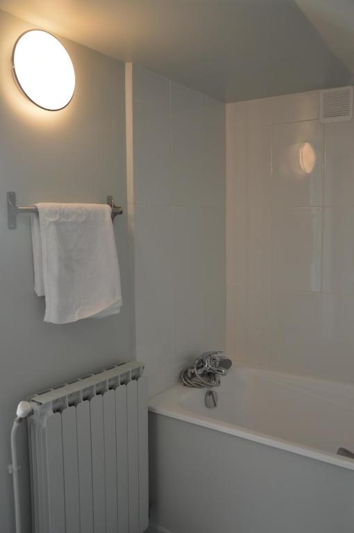 a bathroom with a white towel and a radiator at Hôtel De Normandie in Amiens