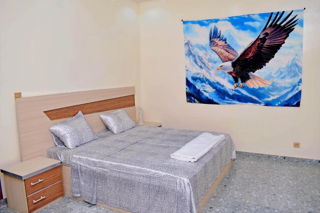 a bedroom with a bed with an eagle painting on the wall at Residence LaFina in Saly Portudal