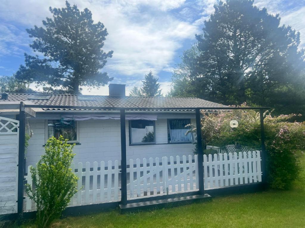 a white house with a white picket fence at Sommerhus in Grevinge