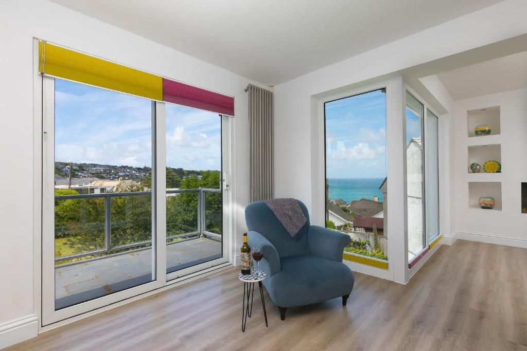 a living room with a blue chair and large windows at Ocean Parc in Carbis Bay
