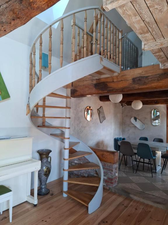 a spiral staircase in a living room with a table and chairs at Chez les Wawas in Sainte-Agathe-dʼAliermont