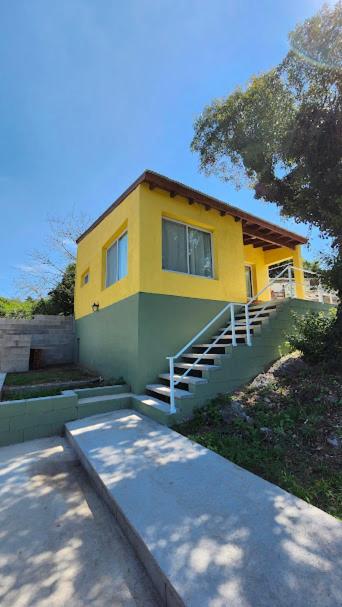 a yellow house with a staircase in front of it at Cabañas Elementos in Huerta Grande