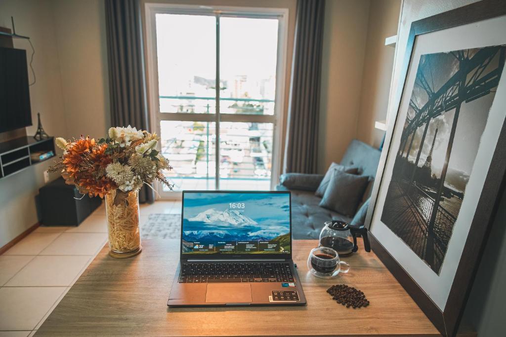 a laptop sitting on a table in a living room at VIVA - Centro - Garagem - Apt 1 Dormitório in Santa Maria