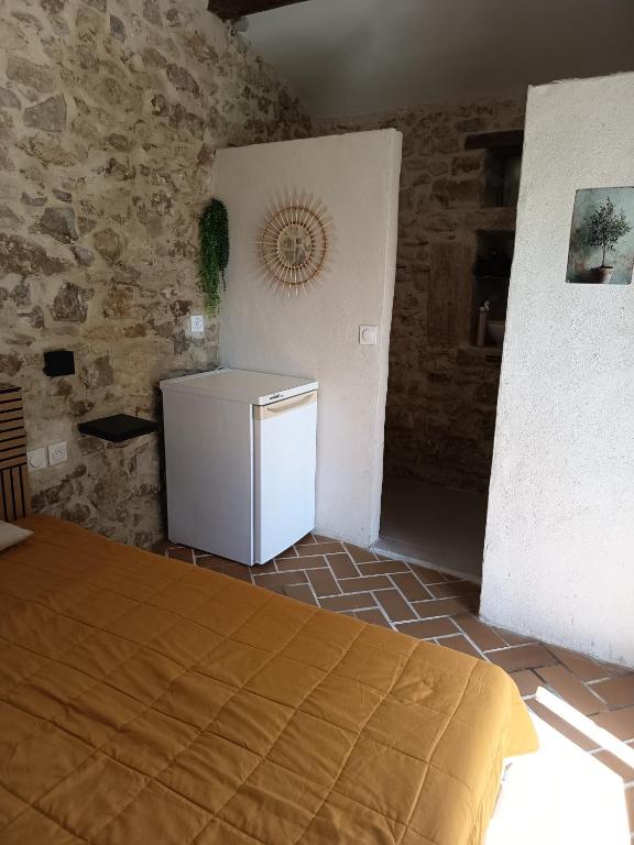 a small refrigerator in a room with a stone wall at Chambre du petit figuier in Aramon