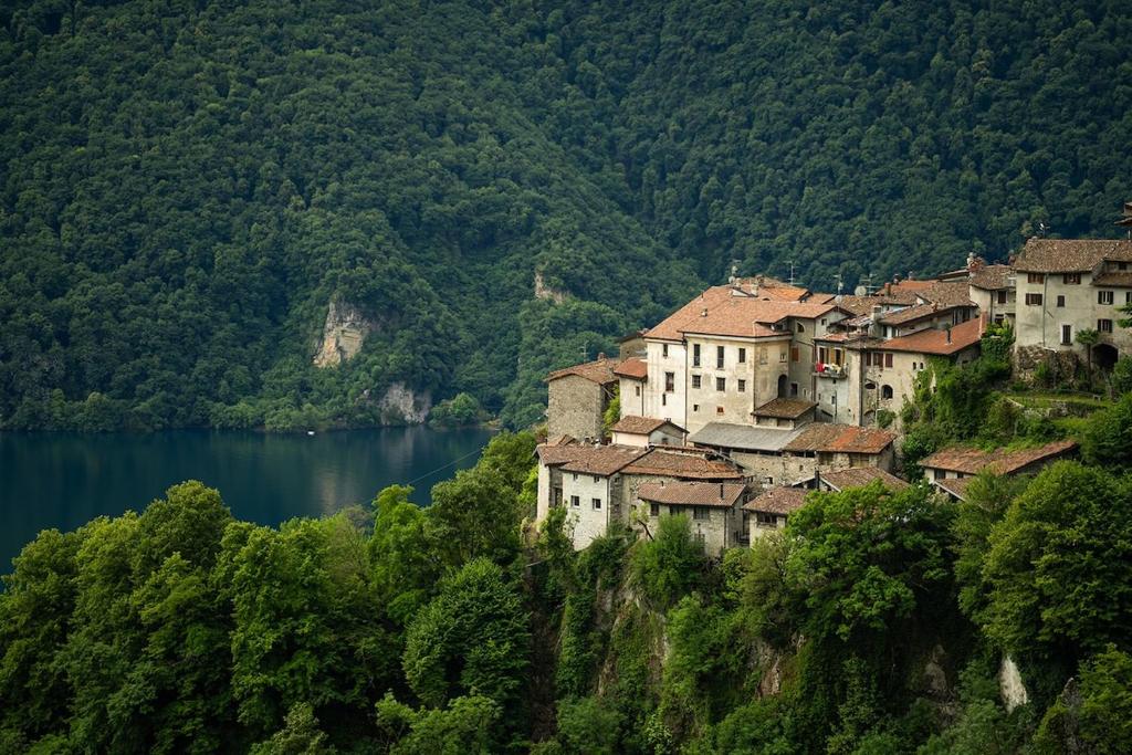 a town on a hill next to a body of water at Puria Rustic Lake View Apartment in Valsolda
