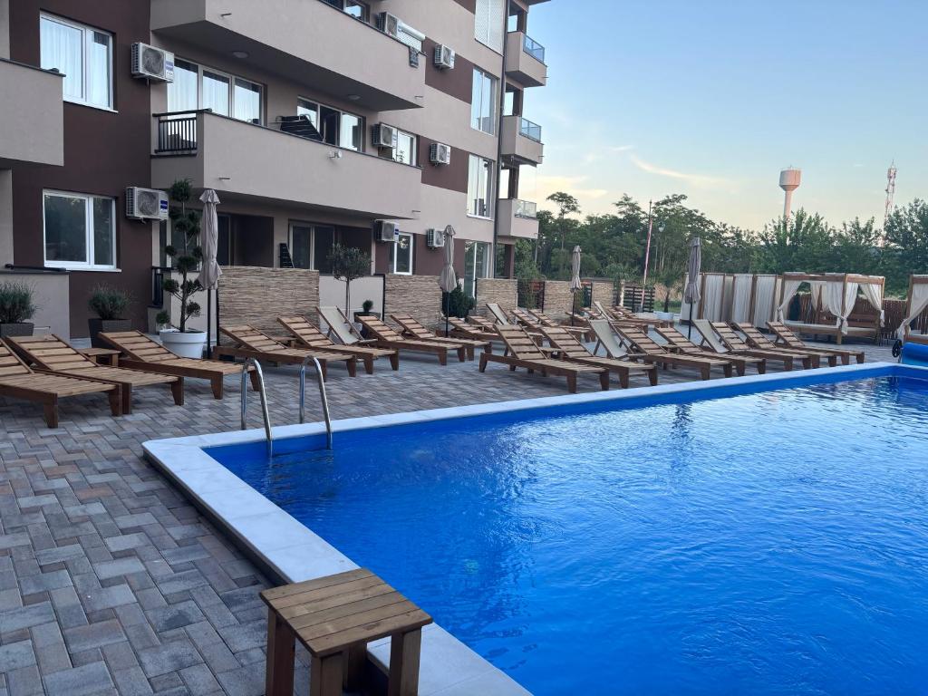 ein Hotelpool mit Liegestühlen neben einem Gebäude in der Unterkunft Šojmesković in Veliko Gradište