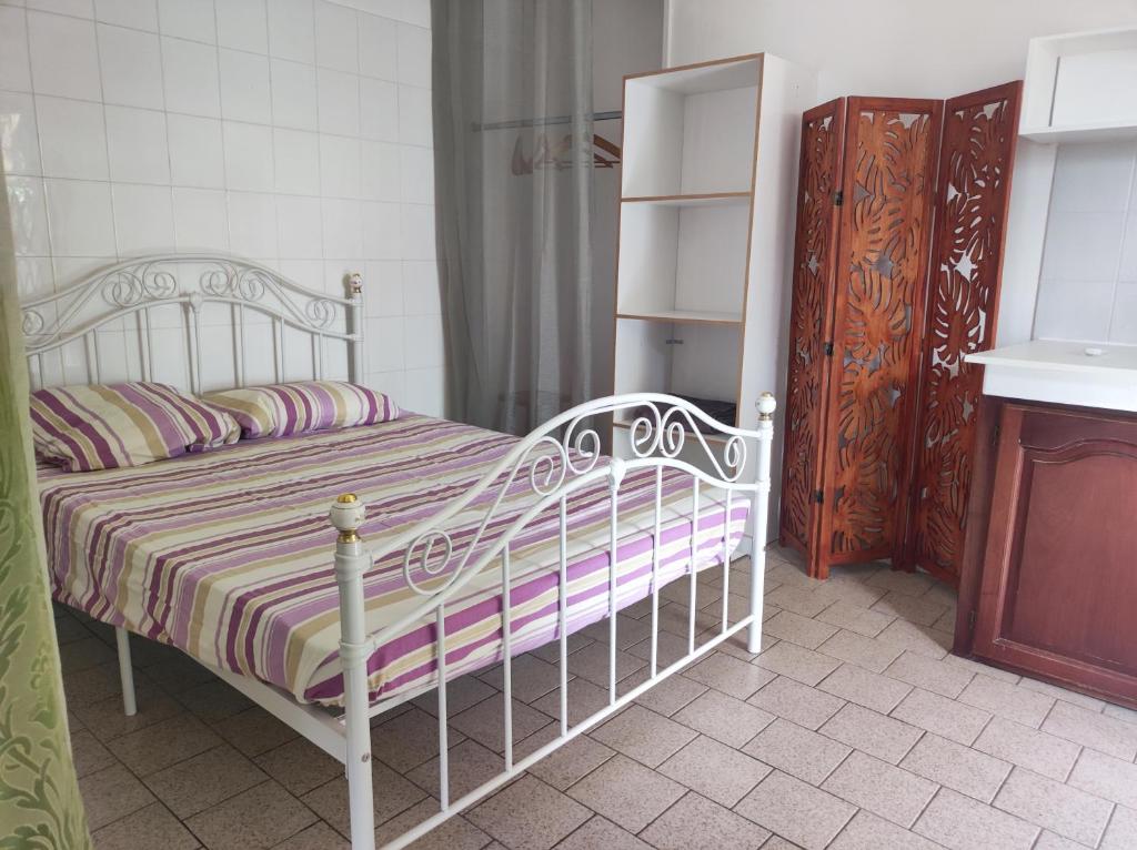 a bedroom with a white bed with a striped blanket at Marilou in Basse-Terre