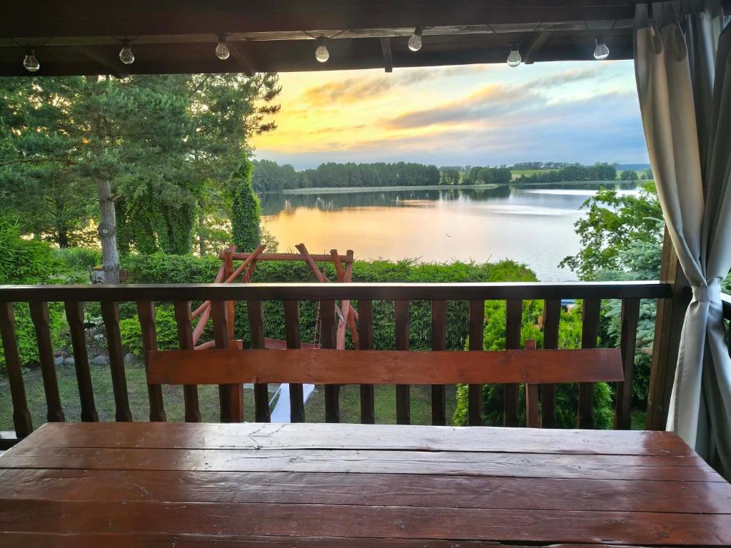 a wooden bench sitting on a porch overlooking a lake at Dom letniskowy ANTOLEK in Ryn