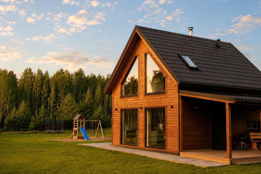a log cabin with a playground in a field at Rumiane Chatki - Domki z Jacuzzi i Basenem in Rybno