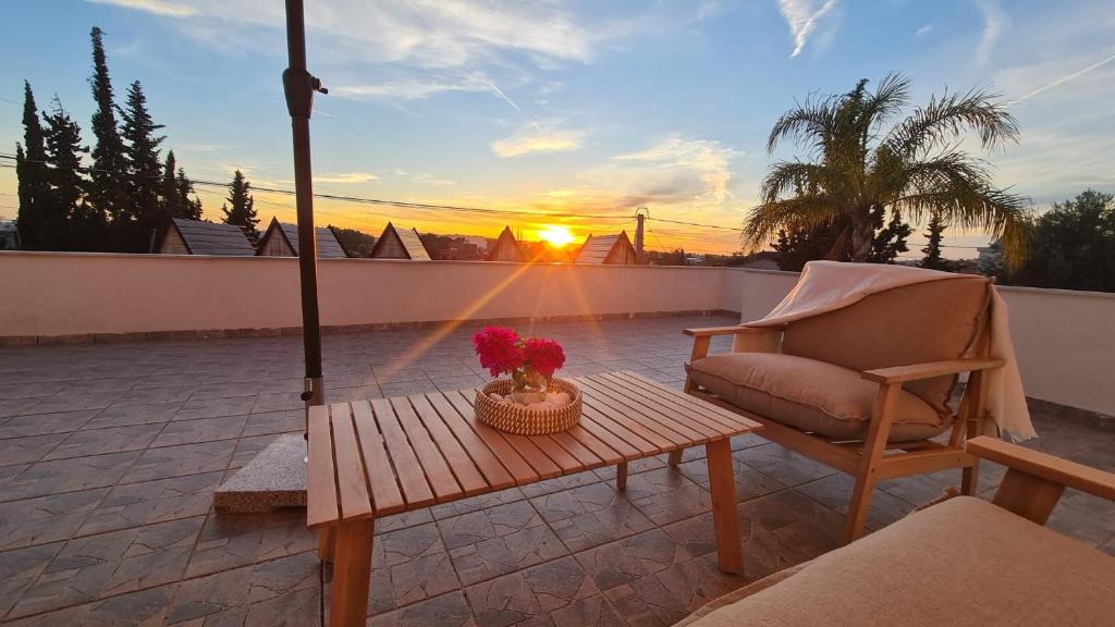a chair and a table on a patio with the sunset at Oasis White in Durrës
