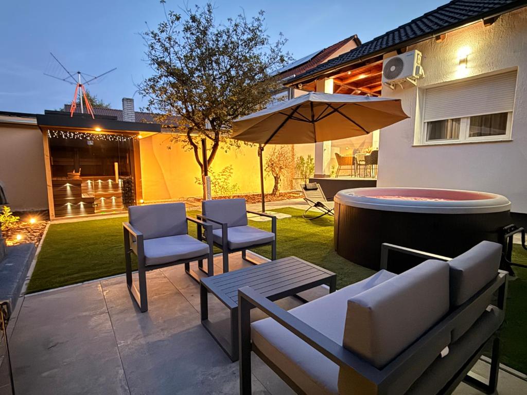 a patio with chairs and a table and an umbrella at CasaBruno Vendégház Celldömölk in Celldömölk