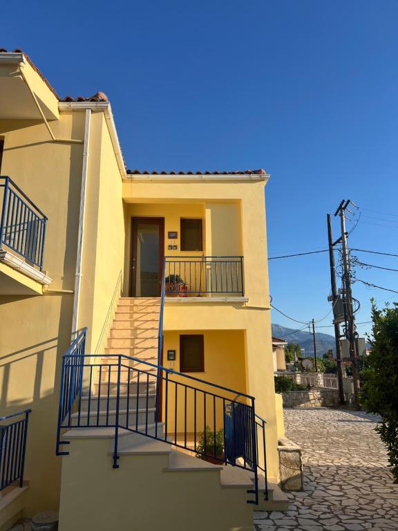 a yellow building with stairs and a balcony at Thalassa Home B in Chiliadou