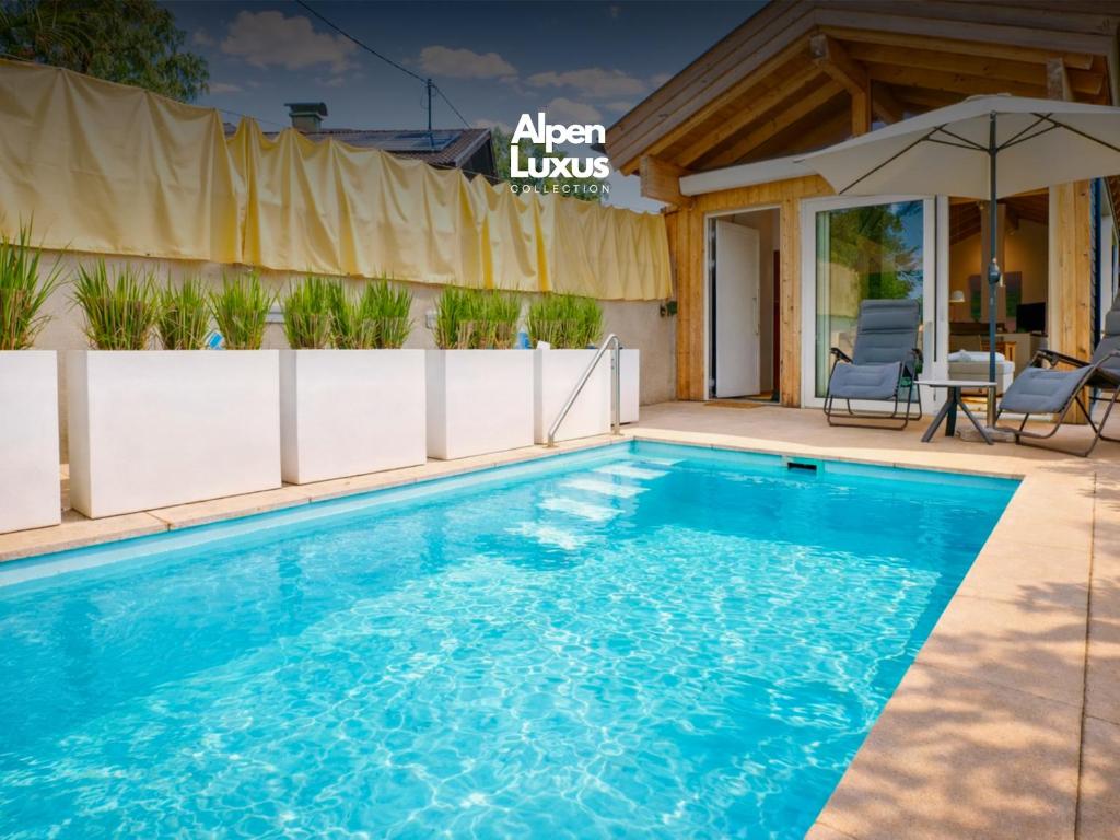 a swimming pool with a patio and an umbrella at Tyrolschalet LITTLE LUCK - Private Pool & Mountain View in Rofansiedlung