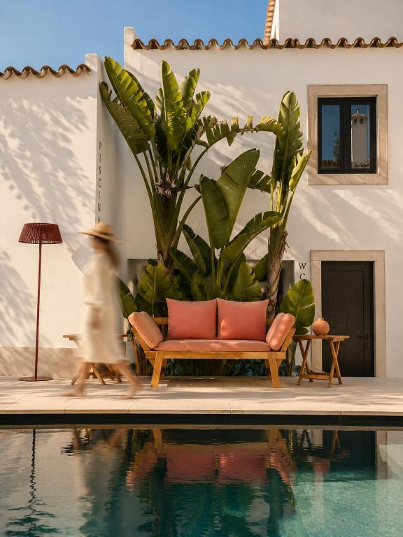a woman walks past a couch next to a pool at A Casa Brava in Santarém