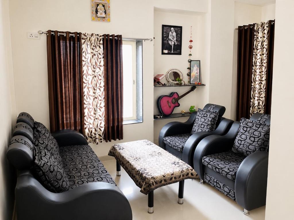 a living room with two chairs and a table at Sai Mahima Stays in Shirdi