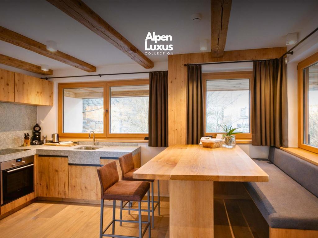 a kitchen with a wooden table and some windows at RACING Suite - Terrace & Sauna Access in Kleinboden