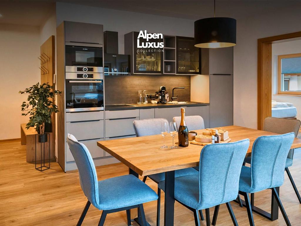 a kitchen and dining room with a wooden table and blue chairs at RUHESTUBE - Design Apartment with Balcony in Fügen