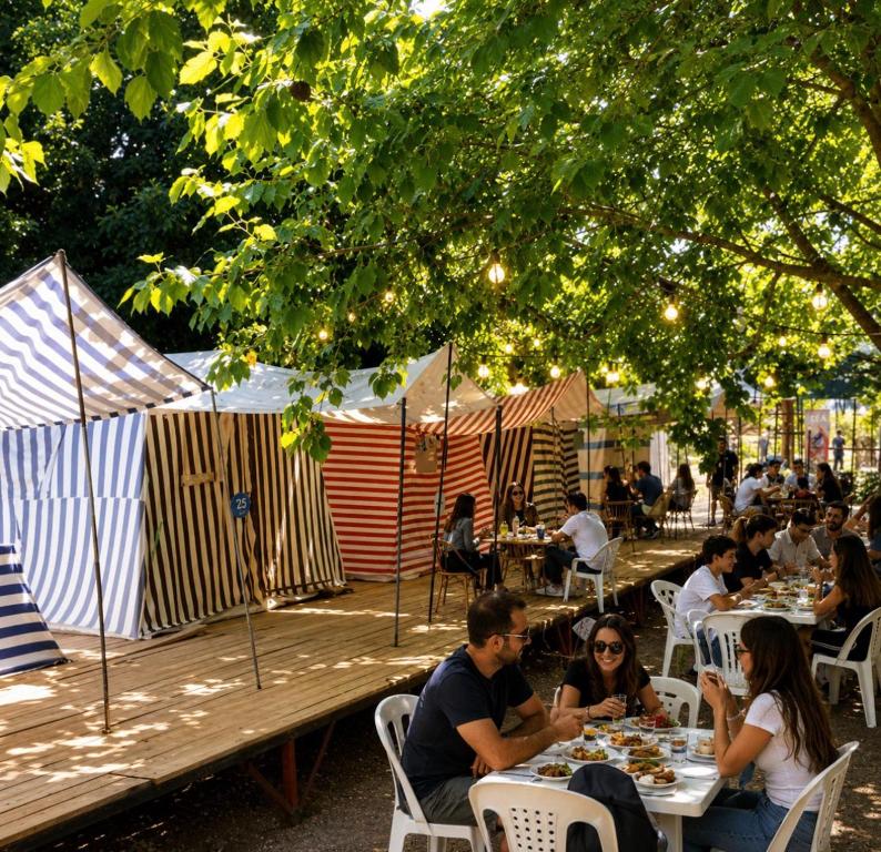 a group of people sitting at tables at an outdoor restaurant at Çıralı Camping in Cıralı