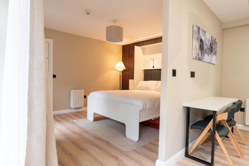 a bedroom with a white bed and a table at Westport Selfcatering Suites in Westport