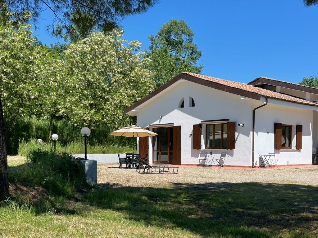a white house with a table and an umbrella at Dolce Collina, Sunset Terrace & Vineyard Views in Dozza