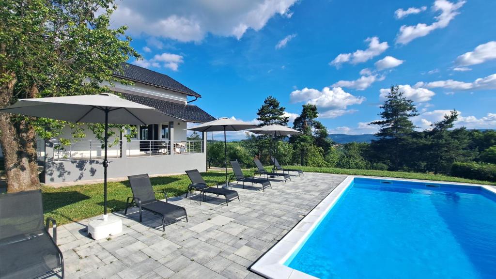 a pool with chairs and umbrellas next to a house at Villa Sunset in Banja Luka