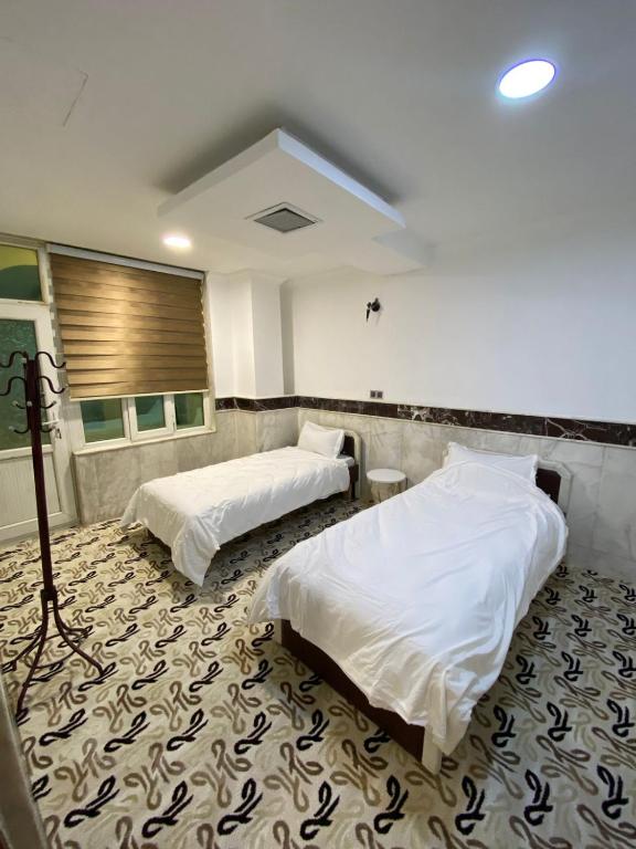a room with two beds on a carpet at Bani motel in Duhok