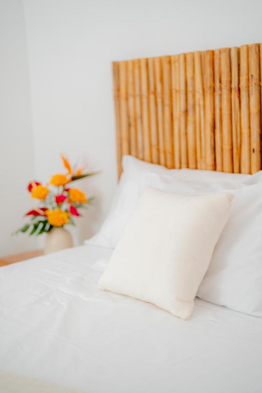 a bed with white pillows and a vase of flowers at Muyuterra in Moyobamba