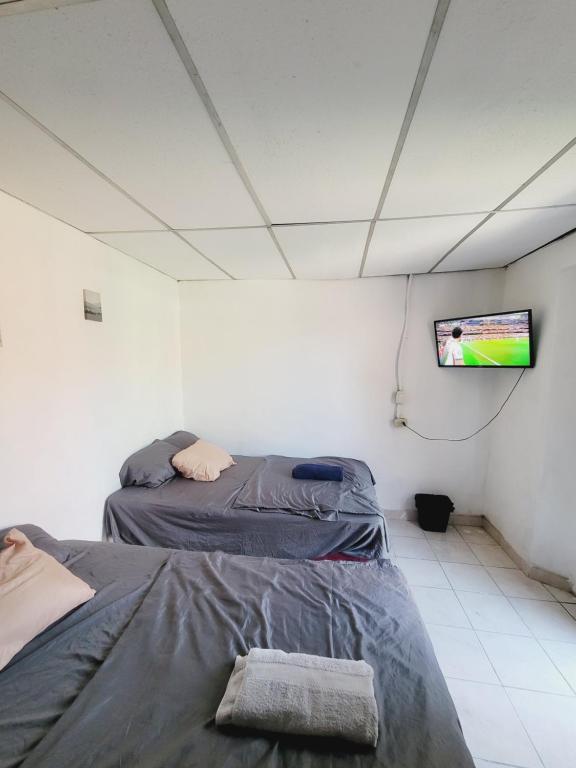 two beds in a room with a tv on the wall at Hospedaje céntrico in Zacatecoluca