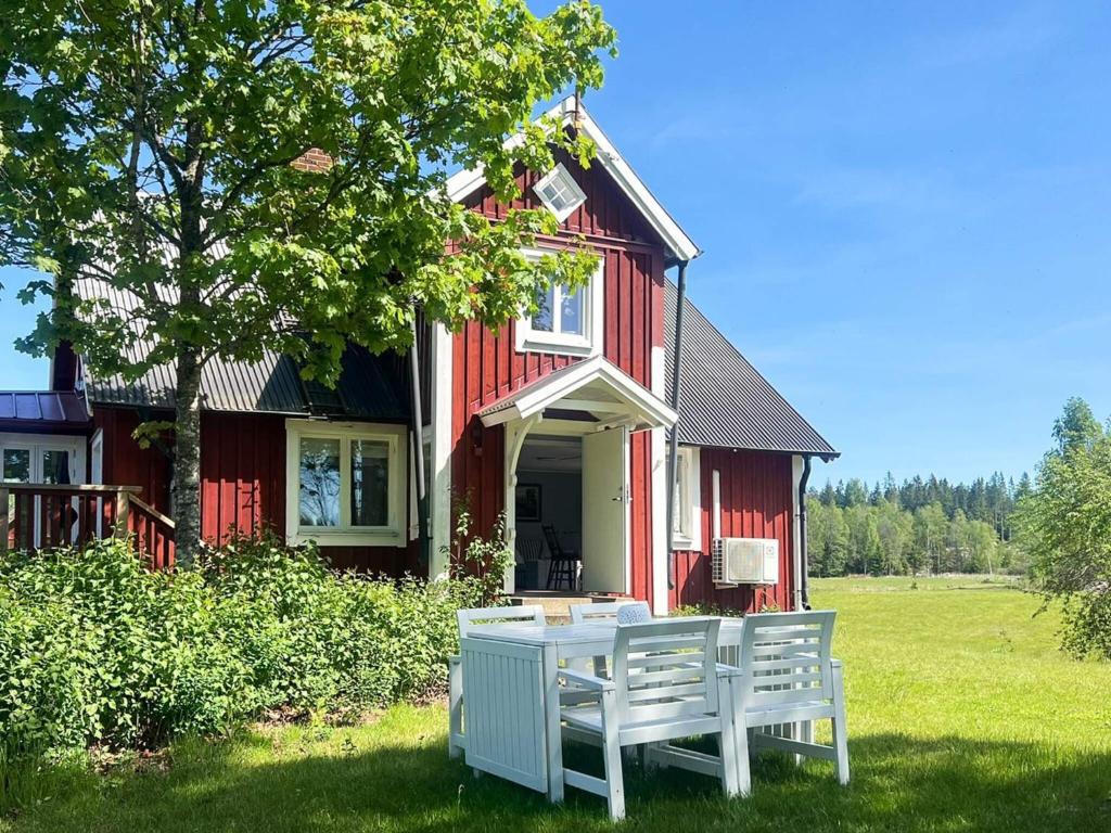 a table and chairs in front of a red house at 5 person holiday home in Häradsbäck in Ryd