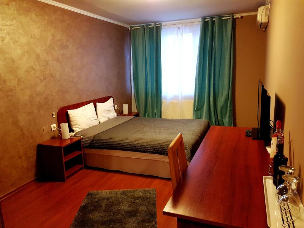 a bedroom with a bed and a window with green curtains at Hotel Mic in Bucharest