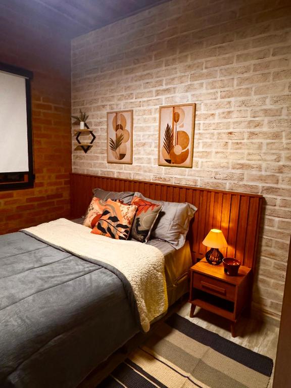 a bedroom with a bed and a table with a lamp at Vila do Sossego in São Bento do Sapucaí