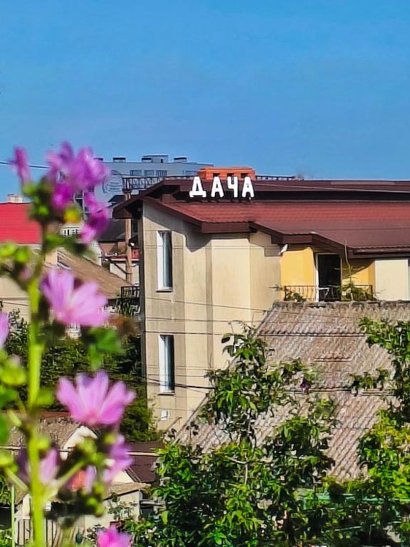 aaa sign on top of a building with pink flowers at Guest House Dacha in Karolino-Buhaz