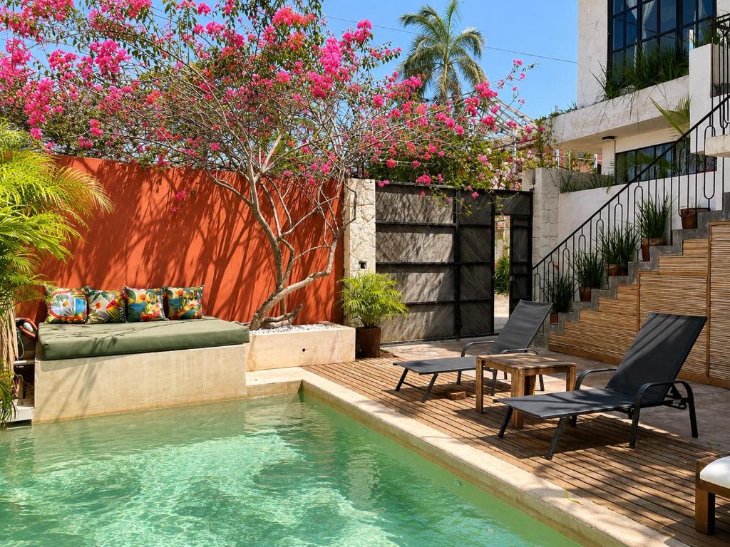 a swimming pool with two chairs and a table and flowers at Maison de Reve - Boutique Guest House in Brisas de Zicatela