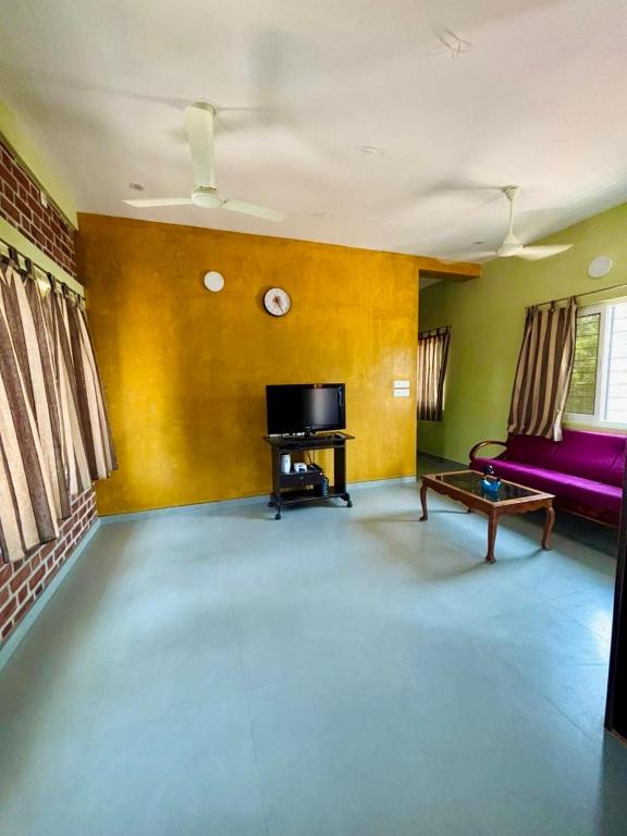 a living room with a purple couch and a table at The Luxora Villa in Kuilapayam