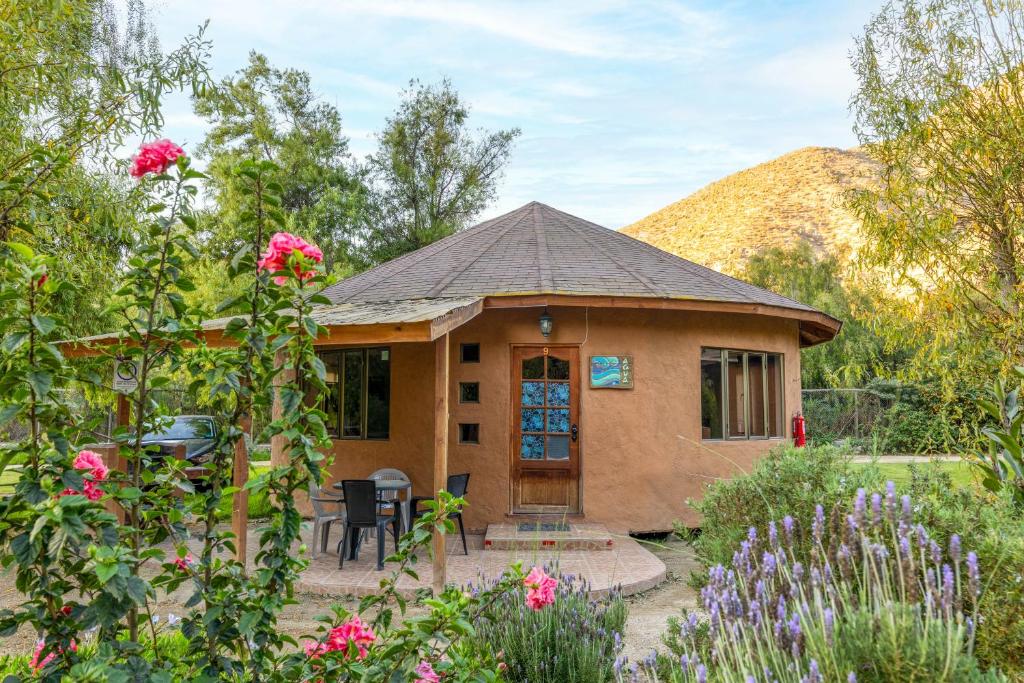 a small house in a garden with flowers at Cabañas Refugio El Molle in El Molle