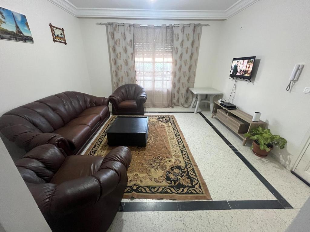 a living room with a leather couch and a table at Les Jasmin Apartment in Menzel Jemil